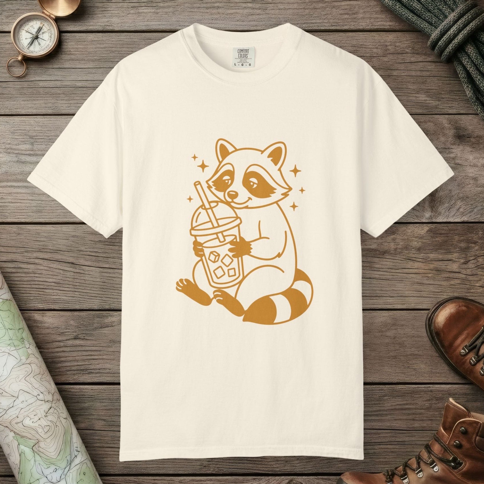 Ivory color unisex graphic t-shirt with "Raccoon with Iced Drink" design